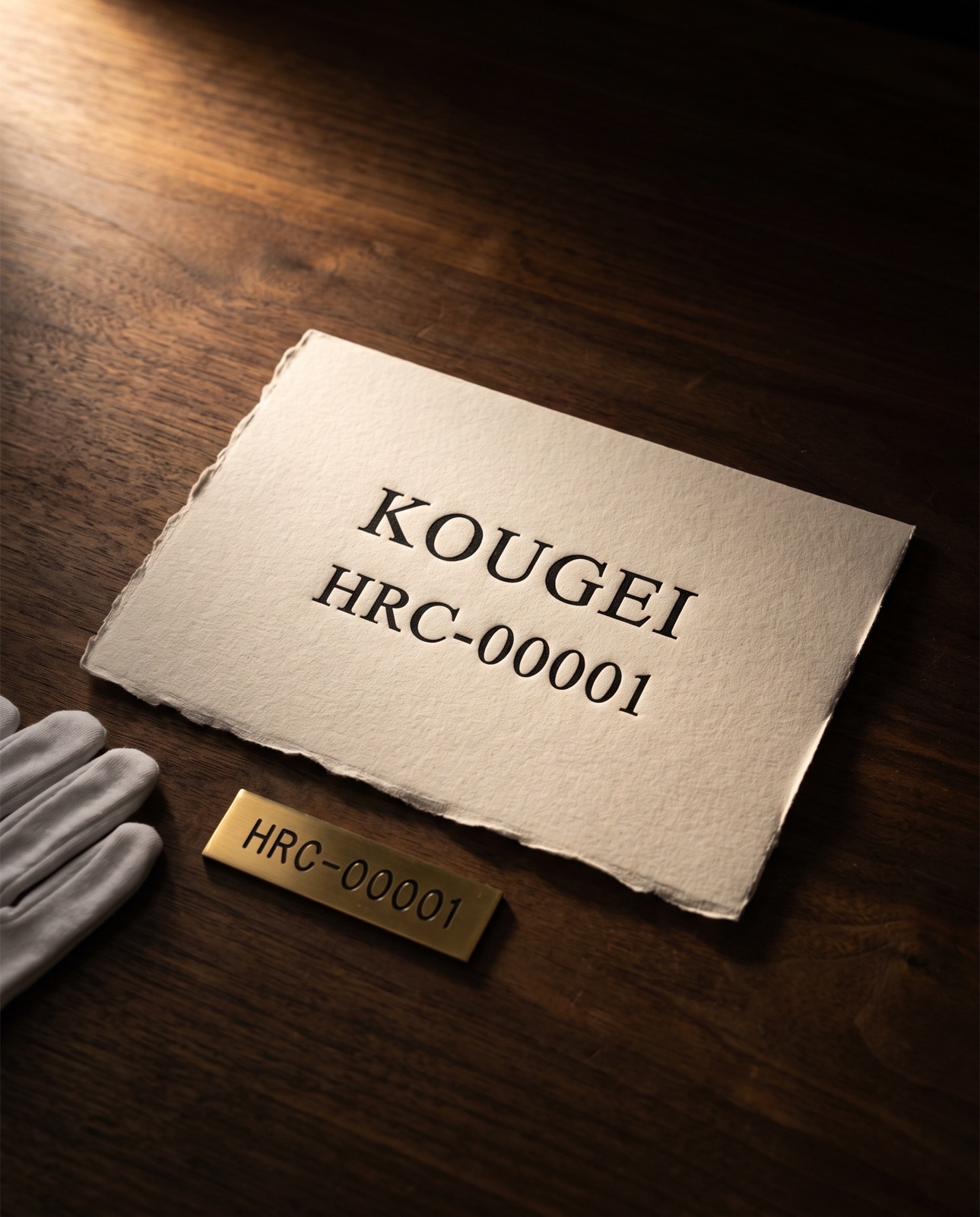 個体情報カードと真鍮のシリアルプレート「KOUGEI HRC-00001」。白手袋とともに